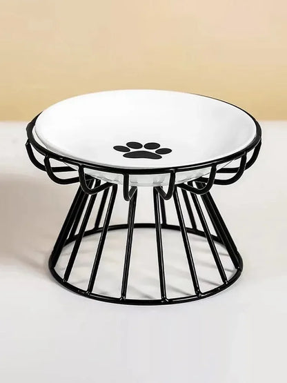 Gamelle surélevée pour chat avec bol en céramique blanche orné d'un motif patte noire, posé sur un support ergonomique en métal noir au design moderne et stable.