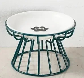 Gamelle surélevée pour chat avec bol en céramique blanche orné d'un motif patte, posé sur un support ergonomique en métal vert sapin au design moderne et stable.
