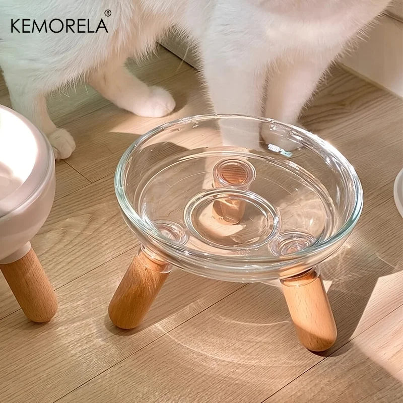 Gamelle surélevée pour chat en verre transparent avec support trépied en bois clair, design scandinave minimaliste et ergonomique pour l'eau ou la nourriture.