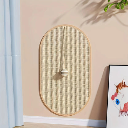 Griffoir chat mural design en sisal tressé de forme ovale. Vue de face d'un griffoir pour chat avec balle de jeu suspendue et cadre en bois clair. Griffoir sisal chat Les Trésors d'Owka, accessoire de protection murale élégant pour décoration intérieure moderne.