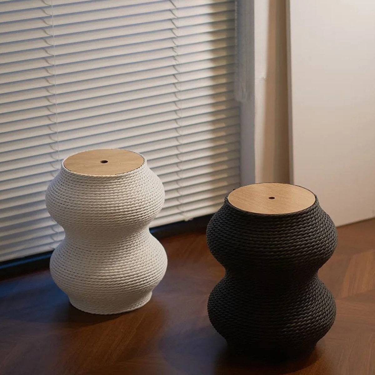 Deux petits griffoirs pour chat en forme de sablier avec plateau supérieur en bois clair, l'un en corde tressée blanche et l'autre en gris anthracite, présentés dans un intérieur moderne.