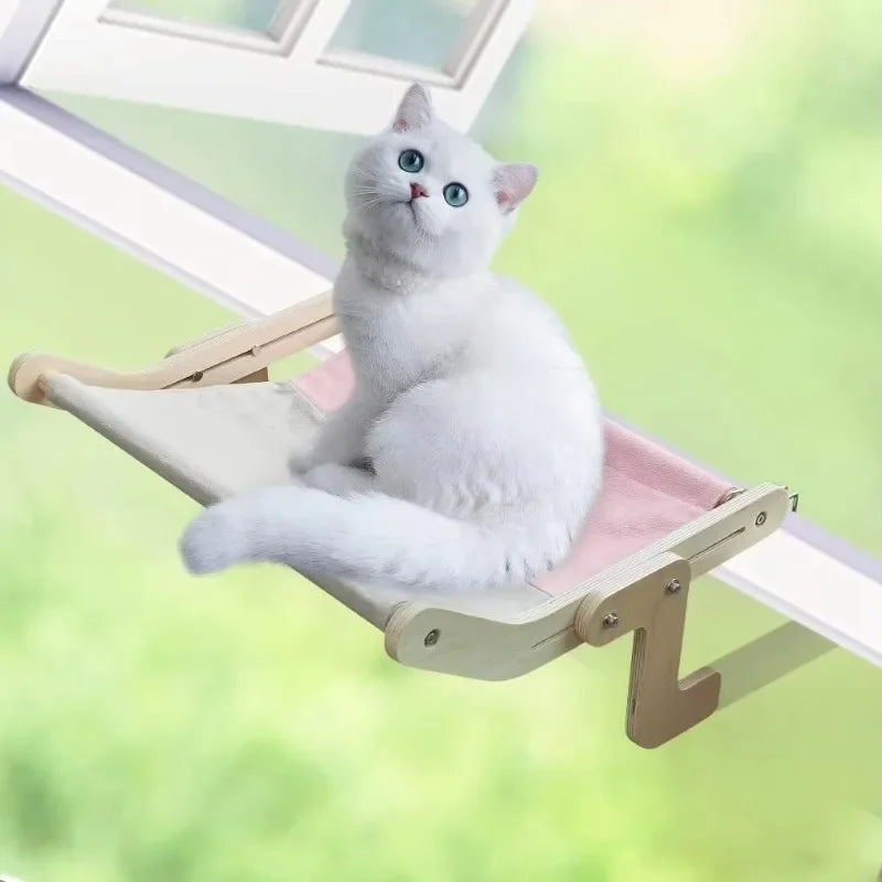 Hamac pour chat en bois naturel avec toile rose et blanche installé sur un rebord de fenêtre. L'image montre un chat blanc assis sur un hamac a chat robuste sans ventouse, fixé par crochets réglables. Lit de fenêtre design scandinave, stable et sécurisé pour hamac pour chat. Qualité Les Trésors d'Owka.