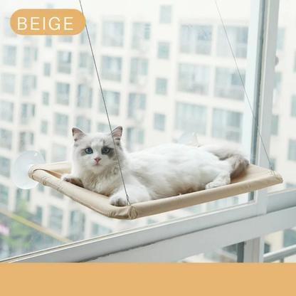 Hamac pour chat beige de fenêtre fixé par ventouses haute résistance. L'image présente un hamac chaton beige au design épuré suspendu sur une vitre avec un chat blanc. Lit de fenêtre confortable, robuste et gain de place pour hamac a chat. Qualité premium Les Trésors d'Owka.