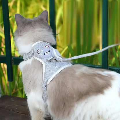 Chat portant un harnais de promenade gris chiné avec motif ourson en extérieur. Ce harnais sécurisé est le complément idéal de tout jouet pour chat pour stimuler les sens en jardin. Offrez une alternative au jouet chat d'intérieur avec cet accessoire parmi les jouet animaux permettant une exploration sécurisée et interactive.