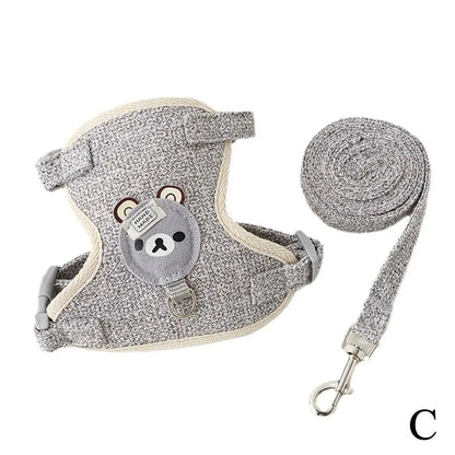 Ensemble harnais pour chat gris chiné avec laisse assortie et motif ours brodé. Ce harnais chat de type veste ergonomique en tissu respirant est doté d'attaches métalliques robustes et d'une laisse rotative. Conçu comme un harnais animaux haute sécurité, il est idéal pour les promenades en extérieur et offre un confort maximal anti-évasion.