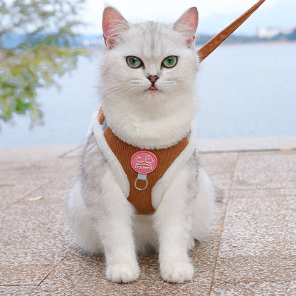 Chat blanc aux yeux verts portant un harnais en velours côtelé marron avec des bordures blanches en peluche douce, présenté de face avec sa laisse assortie. Ce gilet molletonné est le support de confort idéal pour placer un collier gps pour chaton tout en protégeant son pelage délicat. Assurez le bien-être de votre animal avec ce harnais élégant, parfaitement compatible avec l'usage d'un collier gps chat pour des promenades sereines grâce à ce support de collier gps haut de gamme.