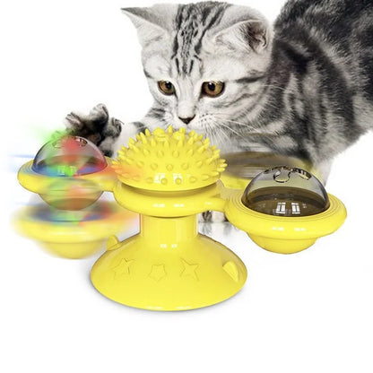 Jouet interactif jaune pour chat en forme de moulin à vent avec ventouse, doté d'une boule de massage centrale et de deux globes rotatifs contenant des billes lumineuses, présenté avec un chaton gris en plein jeu.
