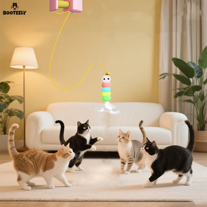 Jouet pour chat automatique Booteely de type ascenseur électrique fixé en hauteur. Quatre chats observent et jouent avec une chenille multicolore à plumes et clochette suspendue par un fil jaune. Ce jouet chat interactif autonome est idéal parmi les jouet animaux pour occuper plusieurs félins en même temps dans un salon moderne.