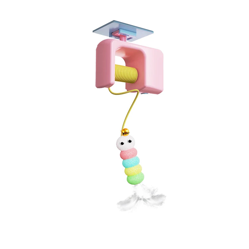 Jouet pour chat automatique de type ascenseur électrique avec boîtier rose et enrouleur. Ce jouet chat interactif suspend une chenille multicolore en pompons munie d'un grelot et de plumes blanches. Un accessoire technologique unique parmi les jouet animaux pour stimuler l'instinct de chasse en toute autonomie grâce à son système de fixation universel.