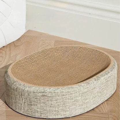 Panier griffoir pour chat de forme ovale avec surface incurvée en carton ondulé haute densité et contour en tissu beige chiné, posé sur un parquet en chevrons.