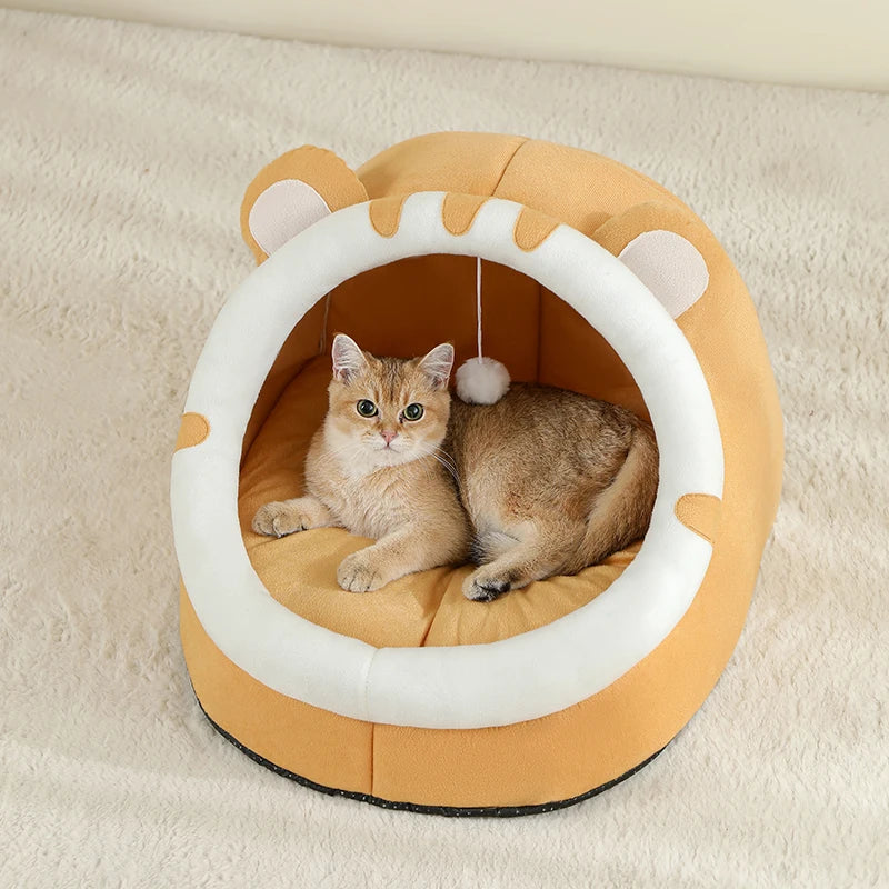 Panier chat igloo orange ocre en peluche ultra-douce avec oreilles décoratives et pompon suspendu. L'image montre un chaton installé sur un coussin pour chat épais à l'intérieur d'un lit cocon fermé. Refuge protecteur, chaud et design pour coussin a chat. Qualité premium Les Trésors d'Owka.