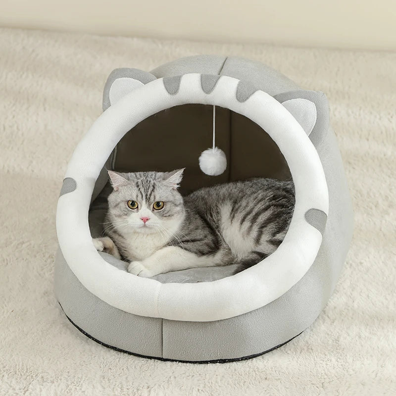 Panier chat en forme d'igloo gris et blanc avec oreilles de chat et pompon suspendu. L'image montre un chat gris installé sur un coussin pour chat épais et moelleux à l'intérieur de la niche. Lit cocon protecteur et design pour coussin a chat. Qualité premium Les Trésors d'Owka.