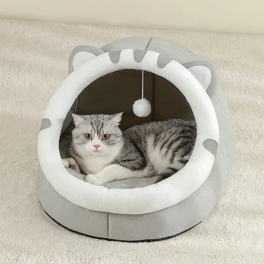 Panier chat en forme d'igloo gris et blanc avec oreilles de chat et pompon suspendu. L'image montre un chat gris installé sur un coussin pour chat épais et moelleux à l'intérieur de la niche. Lit cocon protecteur et design pour coussin a chat. Qualité premium Les Trésors d'Owka.