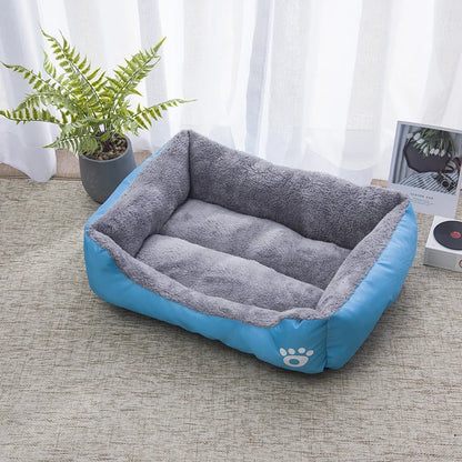 Panier chat rectangulaire bicolore bleu et gris avec intérieur en peluche Sherpa douce. L'image montre ce coussin pour chat confortable avec logo patte blanche dans un salon moderne. Lit douillet, spacieux et résistant pour un confort type coussin a chat. Qualité premium Les Trésors d'Owka.
