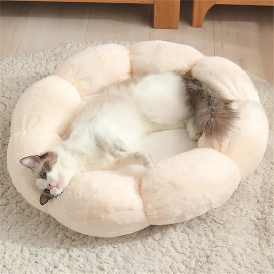 Chat siamois s'étirant confortablement dans un panier pour chat en forme de fleur couleur crème, réalisé en peluche ultra-douce avec pétales rembourrés pour un effet cocooning.
