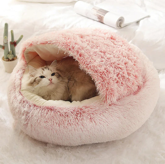 Chat à poils longs niché dans un panier rond apaisant avec toit protecteur en peluche rose et blanche, offrant un intérieur douillet et une isolation thermique optimale.