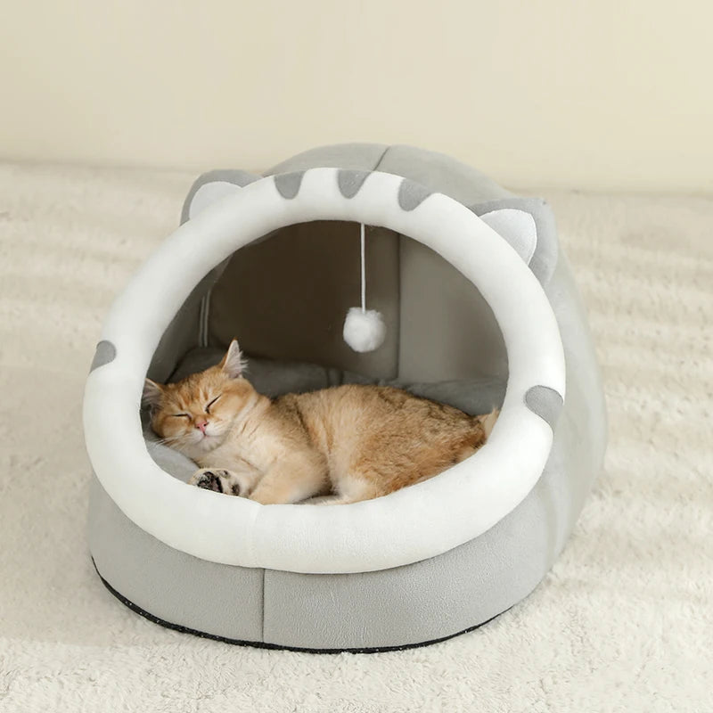 Panier chat en forme de niche igloo grise avec oreilles et pompon blanc. L'image montre un chaton endormi sur un coussin pour chat ultra-moelleux et confortable. Refuge protecteur et chaud pour coussin a chat. Qualité premium Les Trésors d'Owka.