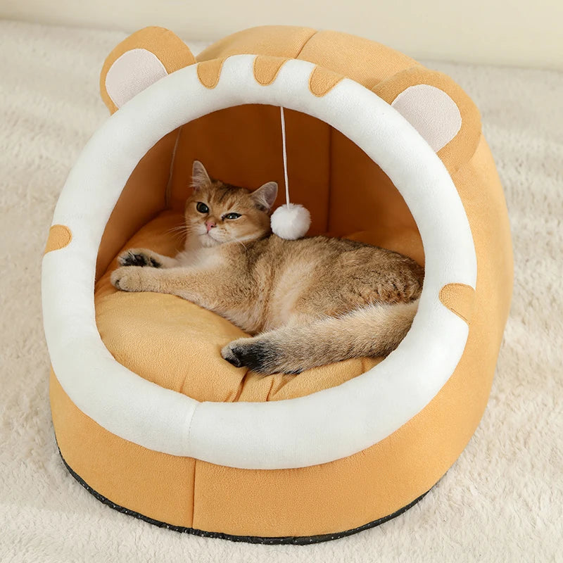 Panier chat orange ocre en forme d'igloo avec oreilles décoratives et pompon blanc suspendu. L'image présente un chaton confortablement installé sur un coussin pour chat épais et moelleux. Lit cocon chaud et sécurisant pour coussin a chat. Qualité premium Les Trésors d'Owka.