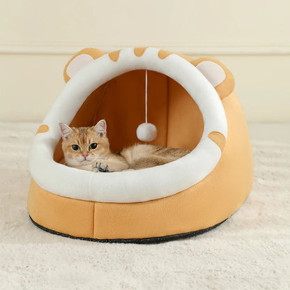 Panier chat igloo orange en peluche douce avec oreilles et pompon suspendu. L'image présente un chaton roux à l'intérieur d'un coussin pour chat fermé et protecteur. Lit cocon ultra-moelleux et design original pour coussin a chat. Qualité premium Les Trésors d'Owka.
