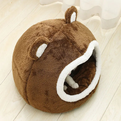 Panier chat en forme d'igloo ours brun avec oreilles blanches et texture peluche épaisse. L'image montre la patte d'un chaton à l'intérieur de ce coussin pour chat fermé et protecteur. Lit cocon douillet, rond et chaud pour un confort type coussin a chat. Qualité supérieure Les Trésors d'Owka.
