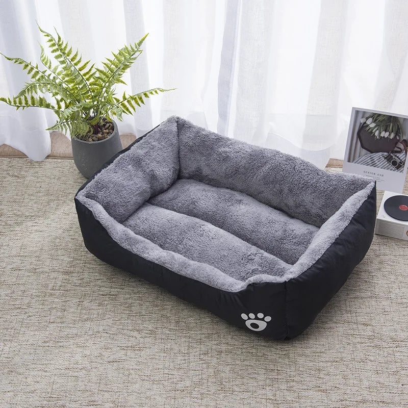 Panier chat rectangulaire noir et gris avec intérieur en peluche douce et rebords capitonnés. L'image présente un coussin pour chat bicolore avec logo patte blanche dans un décor zen. Lit douillet, isolant et facile d'entretien pour un confort type coussin a chat. Qualité supérieure Les Trésors d'Owka.
