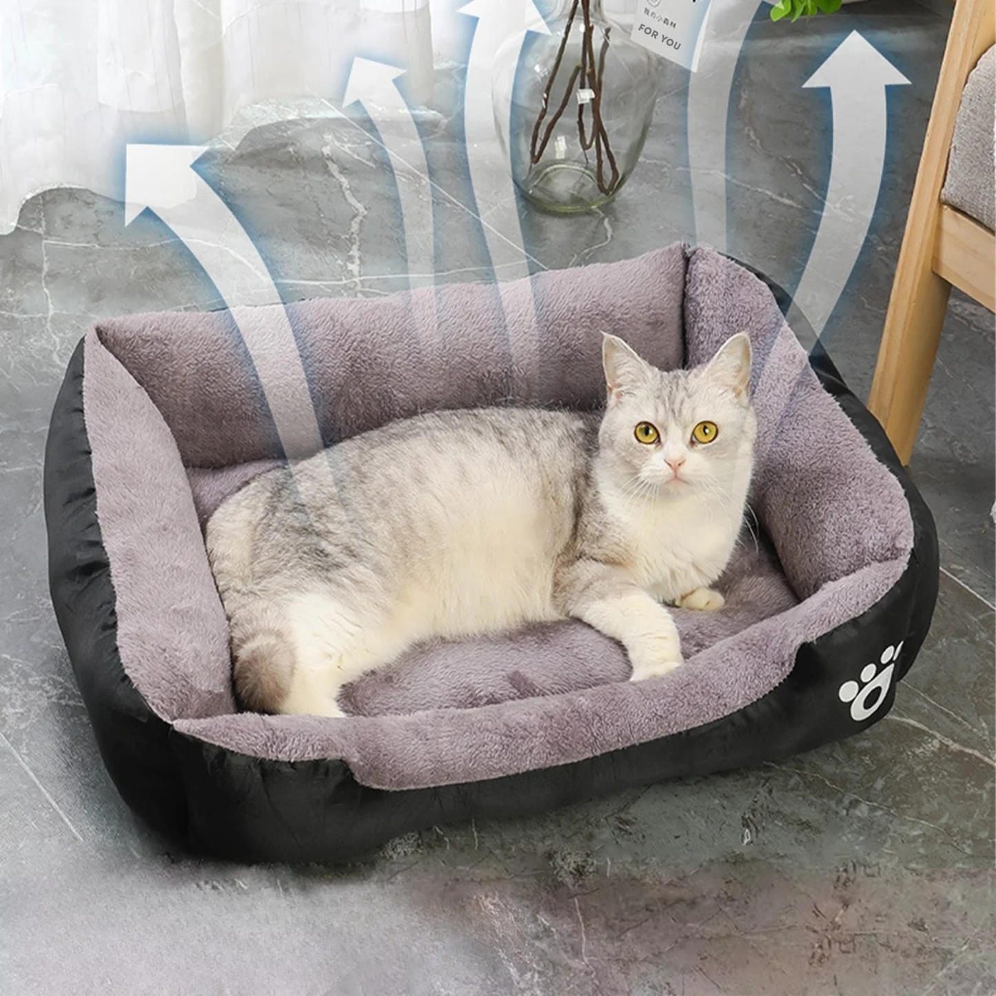 Panier chat rectangulaire bicolore noir et gris avec flèches illustrant la respirabilité du tissu. L'image présente un chaton sur un coussin pour chat épais en peluche grise. Lit douillet, aéré et anti-odeur pour un confort de type coussin a chat. Qualité Les Trésors d'Owka.