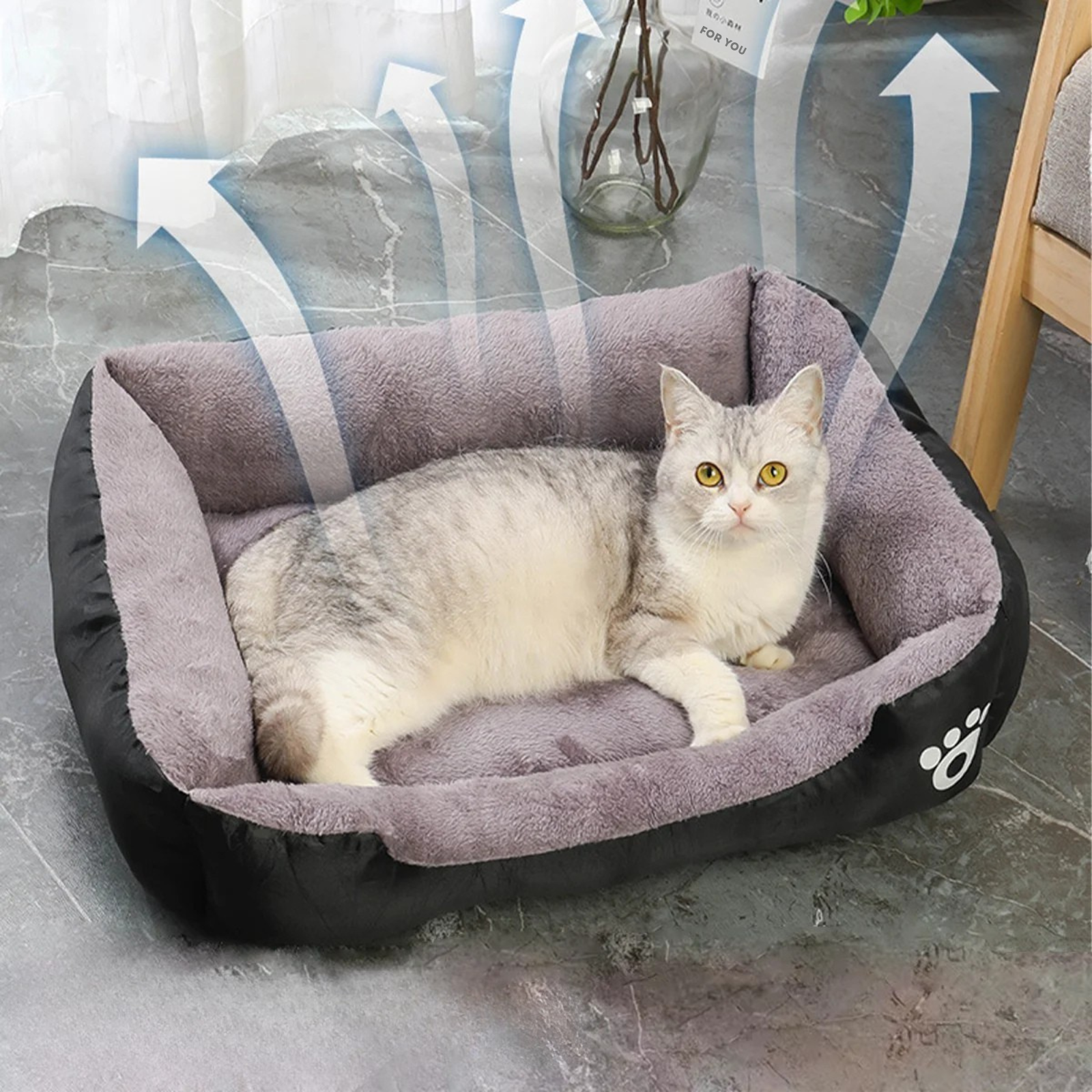 Panier chat rectangulaire bicolore noir et gris avec flèches illustrant la respirabilité du tissu. L'image présente un chaton sur un coussin pour chat épais en peluche grise. Lit douillet, aéré et anti-odeur pour un confort de type coussin a chat. Qualité Les Trésors d'Owka.