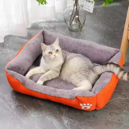 Panier chat bicolore orange et gris avec intérieur en peluche douce et rebords rembourrés. L'image présente un chaton gris étendu dans ce coussin pour chat spacieux avec logo patte. Lit douillet, isolant et design pour coussin a chat. Qualité premium Les Trésors d'Owka.