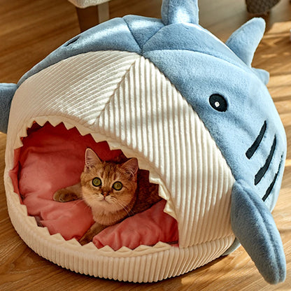 Panier chat original design requin bleu avec nageoires et dents. L'image présente une niche igloo avec un coussin pour chat intérieur rose moelleux et capitonné. Lit design, chaud et protecteur en velours pour un confort de type coussin a chat premium. Qualité Les Trésors d'Owka.