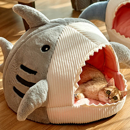Panier chat original en forme de requin gris anthracite avec nageoires et dents. L'image montre une niche igloo avec un coussin pour chat intérieur rose très moelleux. Lit design, chaud et protecteur en velours pour un confort de type coussin a chat premium. Qualité Les Trésors d'Owka.