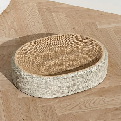 Lit griffoir pour chat de forme ovale avec surface de griffage incurvée en carton ondulé haute densité et revêtement extérieur en tissu beige chiné, posé sur un parquet en chevrons.