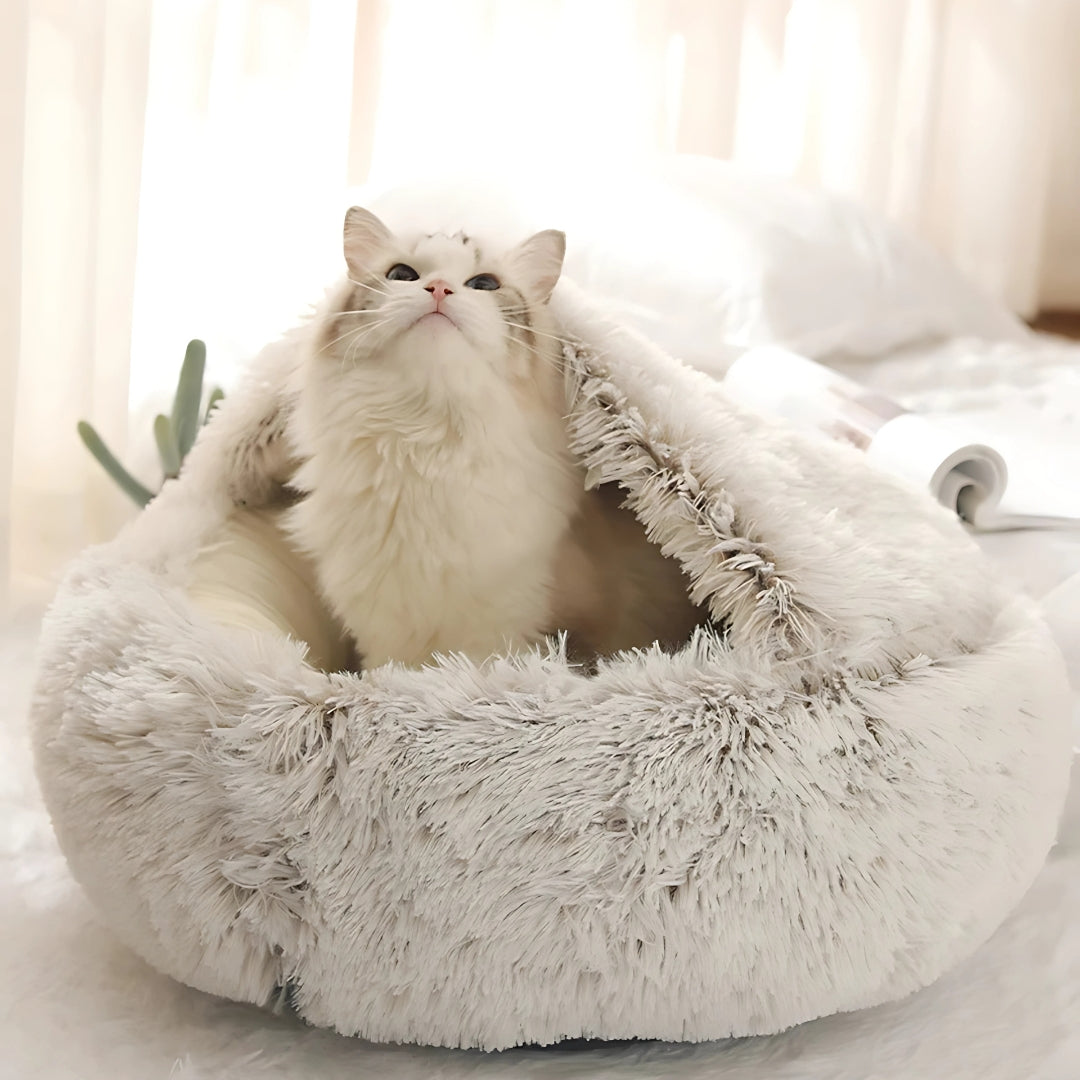 Chat blanc à poils longs installé dans un panier grotte apaisant beige crème en peluche shaggy ultra-moelleuse, offrant un refuge sécurisant et un confort thermique optimal.