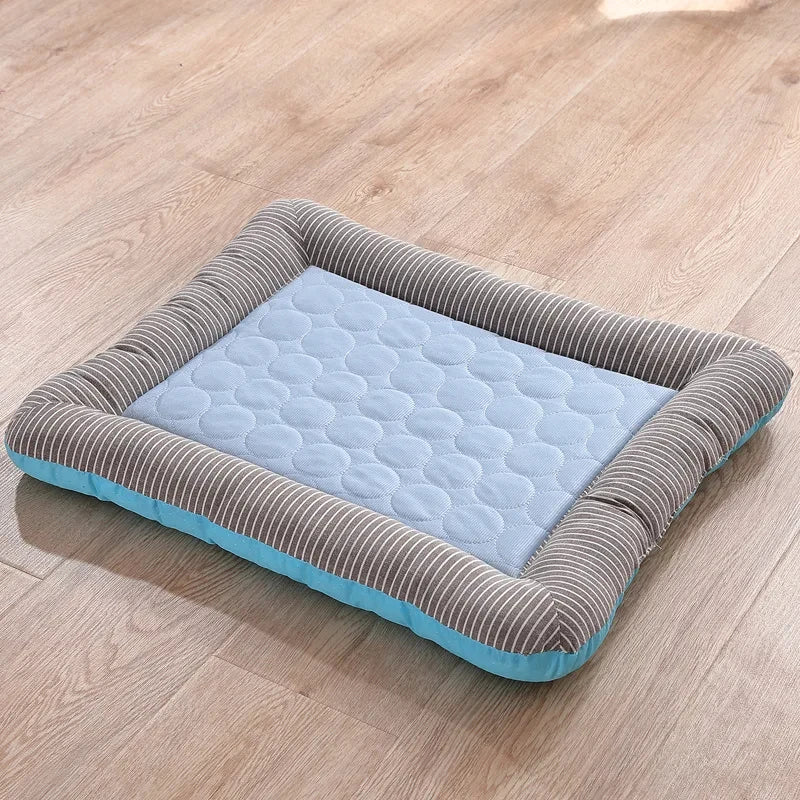 Tapis rafraichissant chien et chat avec bords rembourrés rayés gris et blanc sur un parquet. L'image montre le lit et coussin rafraichissant pour chat bleu matelassé avec une technologie textile soie glacée. Panier d'été auto-rafraîchissant, respirant et confortable. Qualité premium Les Trésors d'Owka.