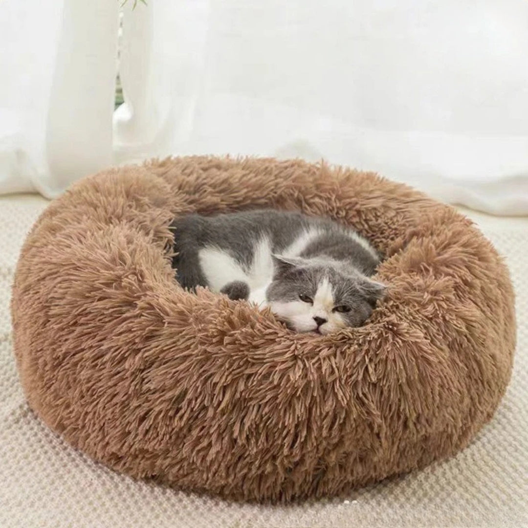 Chaton gris et blanc dormant profondément dans un panier rond apaisant en fausse fourrure marron, avec des bords hauts rembourrés pour un effet nid sécurisant.