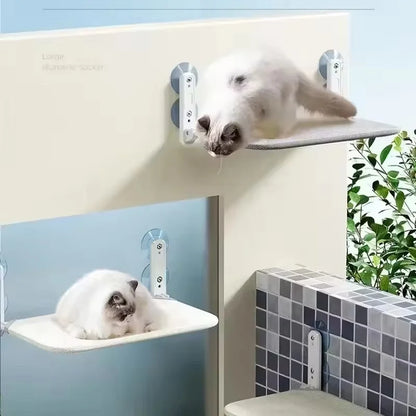 Plusieurs unités de hamac pour chat de fenêtre pliable sans câbles installées en escalier. L'image montre deux chats blancs grimpant et se reposant sur les hamacs chaton beige. Système de fixation à ventouses puissantes pour créer un espace vertical sécurisé. Lit de fenêtre moderne et modulable pour hamac a chat. Qualité Les Trésors d'Owka.