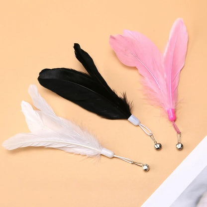 Trio de plumeaux de rechange pour jouets de chat aux couleurs blanc, noir et rose vif, équipés chacun d'un grelot argenté et d'un crochet de fixation métallique.
