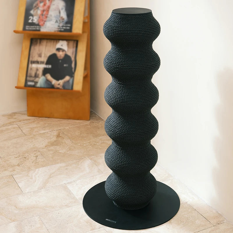 Haut poteau à griffer sculptural pour chat en forme de colonne ondulée noire, fabriqué en corde tressée haute densité sur une base circulaire stable.
