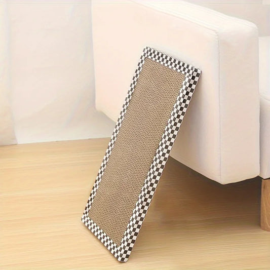 Planche à griffer pour chat en carton ondulé haute densité avec bordure à damier noir et blanc, appuyée contre un canapé blanc pour protéger le mobilier des griffades.