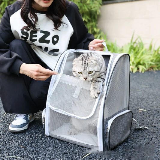 Femme interagissant avec son chat dans un sac à dos pour chat gris et blanc ventilé. Le chat sort la tête du sac dos pour chat Les Trésors d'Owka lors d'une sortie en extérieur. Sac dos chat avec maille mesh respirante idéal pour les balades et le transport sécurisé.