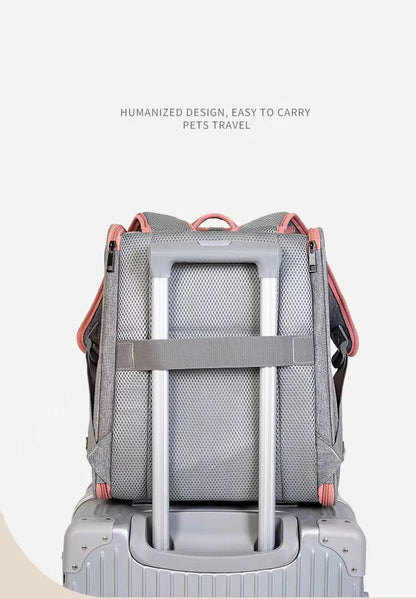 Vue arrière d'un sac à dos de transport pour chat gris et rose fixé sur la poignée télescopique d'une valise grâce à sa sangle trolley intégrée et son dossier en maille respirante.