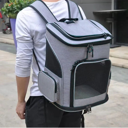 Homme portant un sac à dos de transport pour chat gris chiné en extérieur, mettant en avant les bretelles rembourrées, la structure stable et les filets de ventilation noirs pour le confort de l'animal.