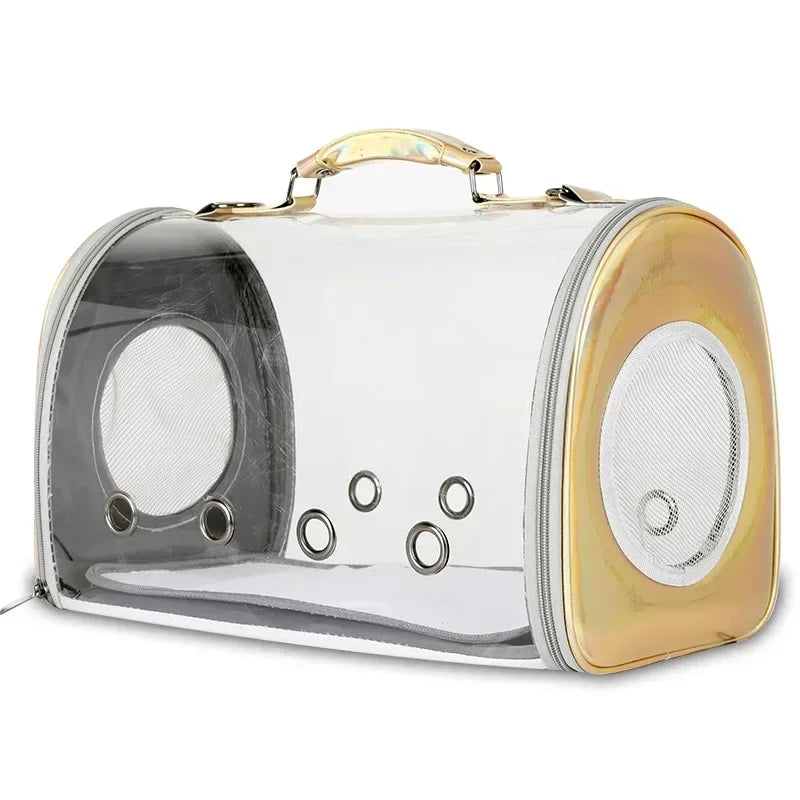 Sac de transport panoramique pour chat et petit chien en matériau transparent rigide avec finitions dorées irisées, équipé de six œillets de ventilation frontaux et d'une poignée de portage ergonomique.