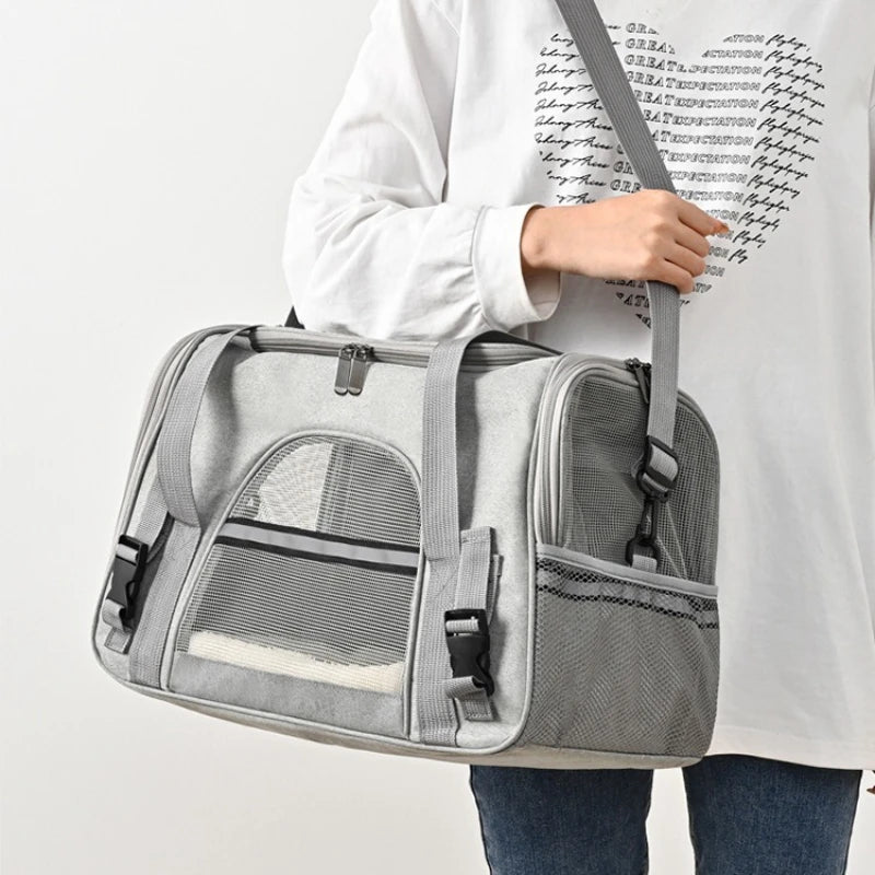 Sac de transport souple pour chat gris clair porté à l'épaule, doté de bandes réfléchissantes de sécurité, de fenêtres en maille respirante et d'un tapis intérieur blanc douillet visible.