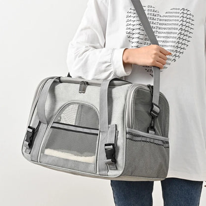 Sac de transport souple pour chat gris clair porté à l'épaule, doté de bandes réfléchissantes de sécurité, de fenêtres en maille respirante et d'un tapis intérieur blanc douillet visible.