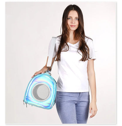 Mannequin portant à l'épaule un sac de transport pour chat bleu ciel holographique aux reflets irisés, illustrant la fenêtre latérale en maille filet pour l'aération et la bandoulière réglable grise.
