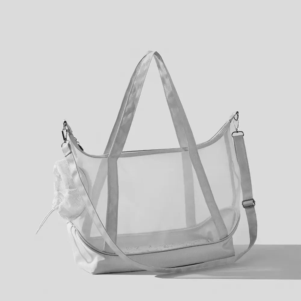 Sac de transport transparent pour chat blanc type tote bag avec vue panoramique, comprenant de grandes anses, une bandoulière d'épaule réglable et un filet de protection souple.