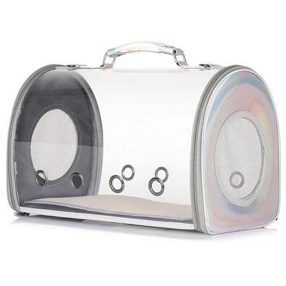Sac de transport rigide pour chat et petit chien avec parois entièrement transparentes, finitions holographiques irisées sur les côtés, poignée de transport supérieure et multiples œillets d'aération frontaux.