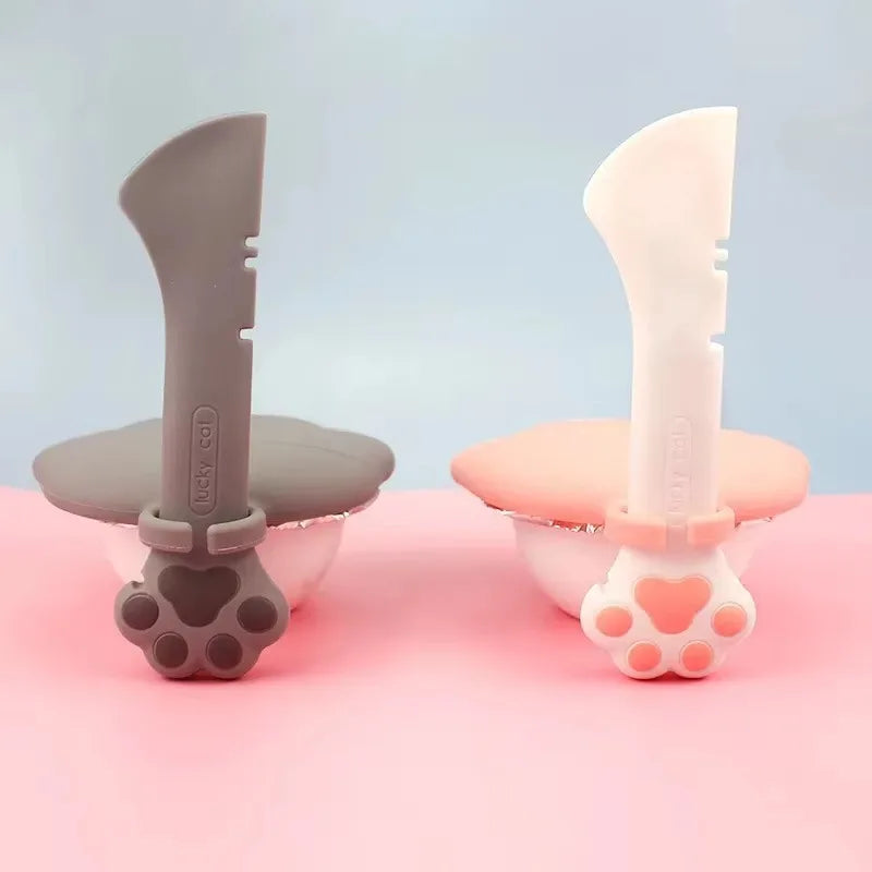 Duo de sets Lucky Cat pour pâtée : modèles gris et blanc avec cuillères ergonomiques clipsées sur couvercles hermétiques en silicone, design patte de chat sur fond bicolore.