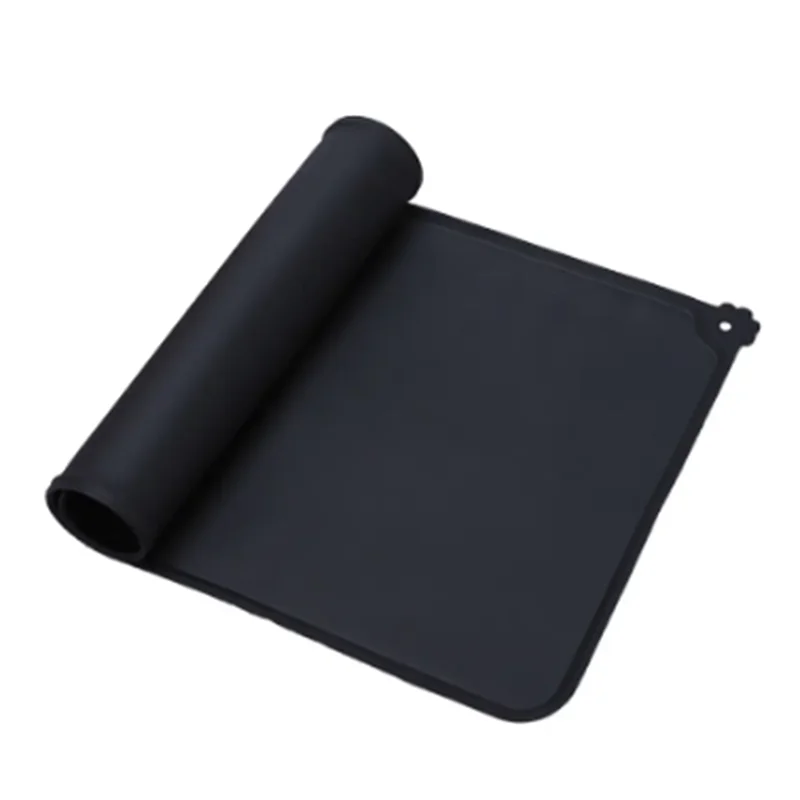 Tapis de gamelle noir en silicone souple partiellement enroulé, imperméable et antidérapant pour chien et chat, avec rebord anti-débordement et motif patte d'animal.