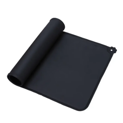Tapis de gamelle noir en silicone souple partiellement enroulé, imperméable et antidérapant pour chien et chat, avec rebord anti-débordement et motif patte d'animal.